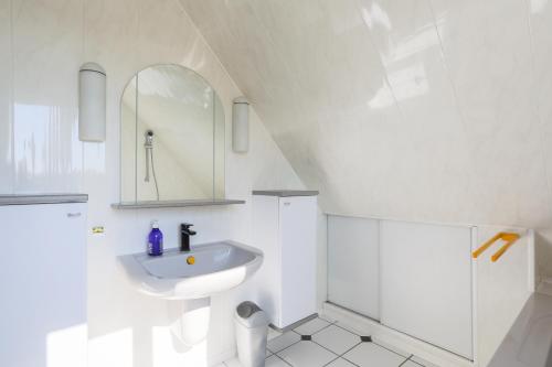 une salle de bain blanche avec un lavabo et un miroir dans l'établissement Charmante Maison Neo-bretonne, à Plérin