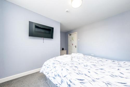 a white bedroom with a bed and a flat screen tv at The Halfway House Inn in Leeds