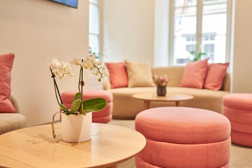 a living room with pink chairs and a table with a vase of flowers at Aparthotel Krone - Self Check-In in Interlaken