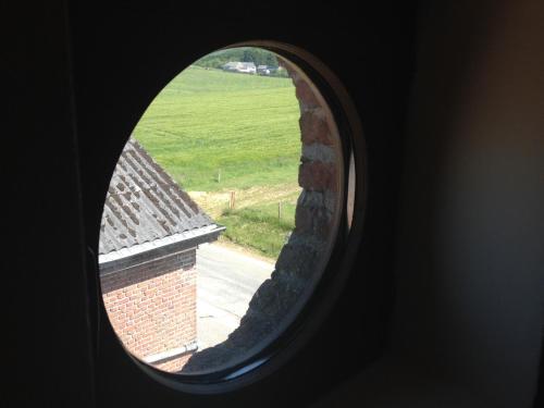 anorthole view of a brick building and a field at Les Gîtes "Le Petit Val" in Durbuy