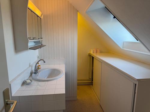 une salle de bain avec un lavabo, un miroir et une fenêtre dans l'établissement La Corniche, à Agon-Coutainville