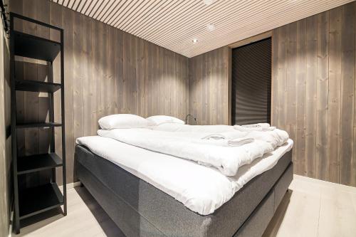 a large bed in a room with wooden walls at Attraktiv leilighet på kaikanten i Henningsvær in Henningsvær