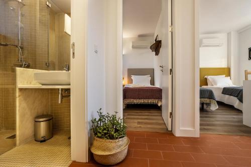 a bathroom with a sink and a bathroom with two beds at QSF Agro Turismo Quinta da Sagrada Família in Évora
