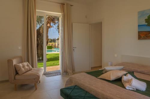 Un dormitorio con una cama y una silla y una ventana. en Villa Di Mola Egnazia and Pool, en Monopoli