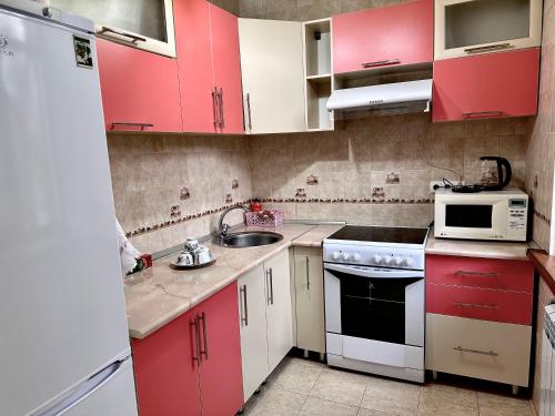 a small kitchen with red cabinets and a sink at Майлина 10 аэропорт in Turksib