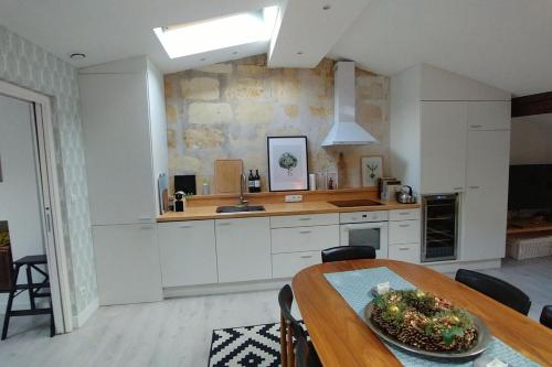 une cuisine avec des armoires blanches et une table en bois dans l'établissement Lovely apartment Bordeaux Jardin Public, à Bordeaux