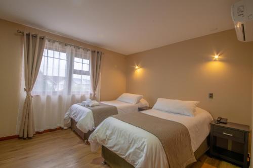 a bedroom with two beds and a window at Gran Hotel Aysen in Puerto Aisén