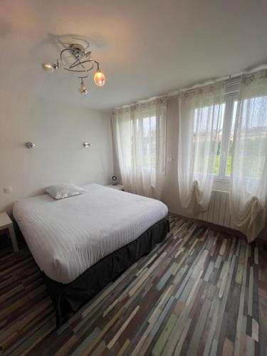 une chambre avec un lit dans une pièce avec des fenêtres dans l'établissement Maison du manoir, à Bénouville
