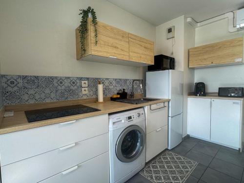 a kitchen with a washing machine and a refrigerator at Stunning T2 pool box-Meyzieu Gare-Stade-Eurexpo in Meyzieu