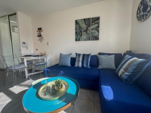 a blue couch in a living room with a table at Stunning T2 pool box-Meyzieu Gare-Stade-Eurexpo in Meyzieu