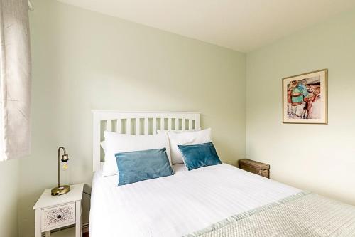 a bedroom with a white bed with blue pillows at Quiet and cosy 2-bed in Wimbledon in London