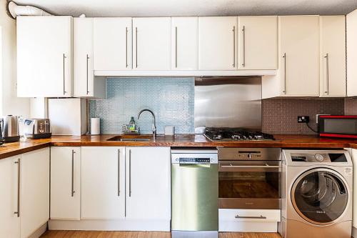a kitchen with white cabinets and a dishwasher at Quiet and cosy 2-bed in Wimbledon in London