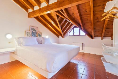 a large white bed in a room with wooden ceilings at Abba Comillas Apartments in Comillas