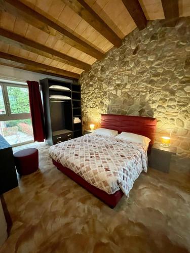 a bedroom with a bed and a stone wall at Modus Aquae in Brisighella