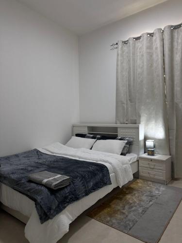 a white bedroom with a large bed and a window at Cozy Studio Retreat in Al Ain in Al Ain