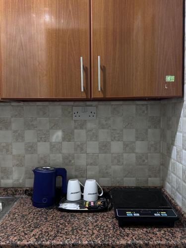 a kitchen counter with two coffee mugs and a laptop at Cozy Studio Retreat in Al Ain in Al Ain