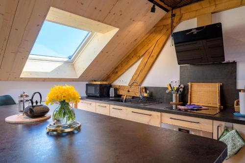 une cuisine avec un vase de fleurs jaunes sur un comptoir dans l'établissement Sous le toit de Marie et Jean, à La Bresse