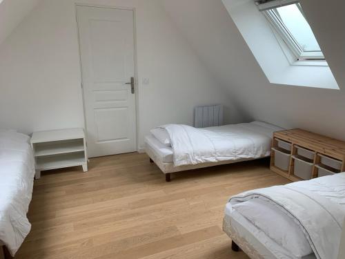 une chambre blanche avec deux lits et une fenêtre dans l'établissement Maison lumineuse à 7mn plages, 5mn de La Trinité, à Saint-Philibert