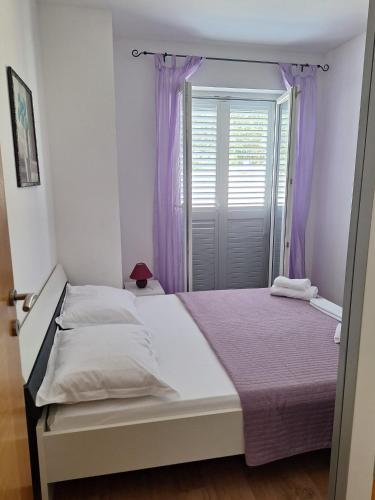 a bedroom with a bed and a window with purple curtains at Villa Tea in Murter
