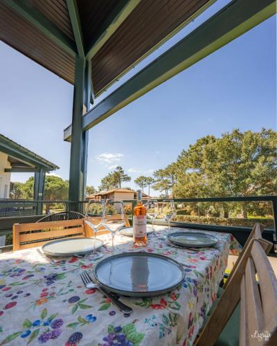 - une table avec des assiettes et une bouteille de vin sur la terrasse dans l'établissement Magnifique appart à 5 min des plages et commerces, à Moliets-et-Maa