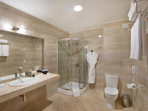 a bathroom with a shower and a toilet and a sink at Park Hotel and SPA Vella Hills in Velingrad