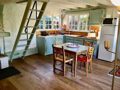 une cuisine avec une table, des chaises et une échelle dans l'établissement Maison de village avec grand jardin, à Chaumont-sur-Tharonne