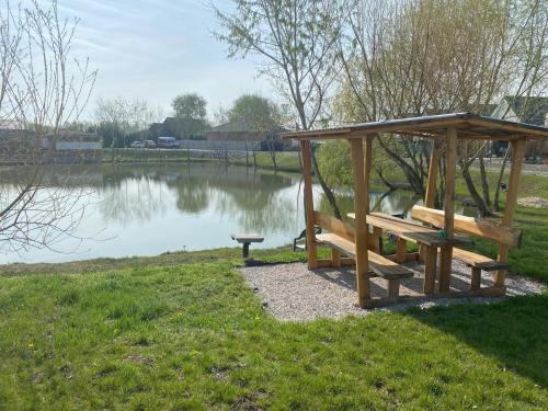 a picnic table and a bench next to a lake at MAX Apartmán pri jazere in Trstice