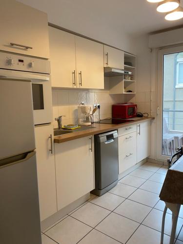 une cuisine avec des armoires blanches et un appareil rouge dans l'établissement Parking privé gratuit, balcon, 2 chambres, à Clermont-Ferrand
