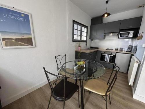 une salle à manger avec une table en verre et des chaises dans une cuisine dans l'établissement Gite bergeron, à Parentis-en-Born