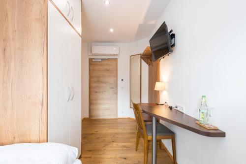 a room with a desk and a tv on a wall at Pension Zum Schrammel in Altdorf bei Nuernberg