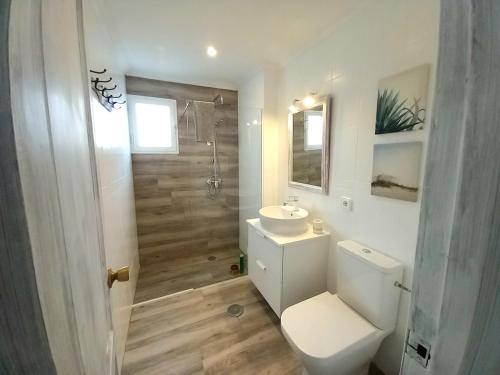 a white bathroom with a toilet and a sink at Beach house near the sea with pool in Puerto del Carmen