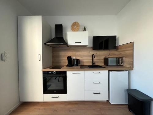 une cuisine avec des armoires blanches et un réfrigérateur blanc dans l'établissement 22B Studio avec Extérieur Coin Nuit & Cuisine, à La Roche-sur-Yon