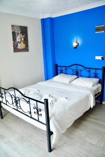 a blue bedroom with a large bed with white sheets at Rebetika Hotel & bistro in Selcuk