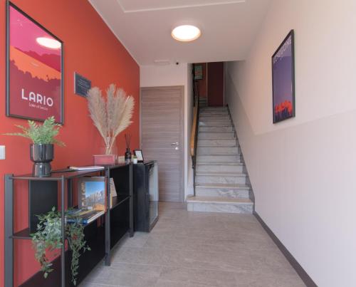 a hallway with a staircase with orange walls and a stair case at Cà del Lasco - Free parking apartments 5 min from the station in Bellano