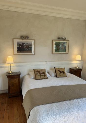 two beds in a bedroom with two pictures on the wall at Domaine de la Geneste in Châteaufort