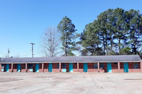 a red and blue building with trees in the background at OYO Hotel Durant MS Bowling Green Rd in Durant