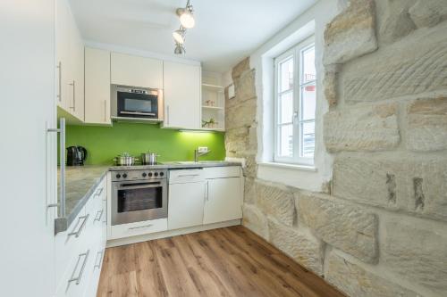 a kitchen with white cabinets and a stone wall at Pension Zum Schrammel in Altdorf bei Nuernberg