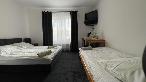 a bedroom with two beds and a television on the wall at Stay Adventure Mrzeżyno in Mrzeżyno