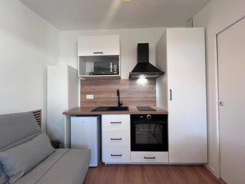 - une cuisine avec des placards blancs, un évier et un canapé dans l'établissement 22 C Cozy and Convenient, à La Roche-sur-Yon