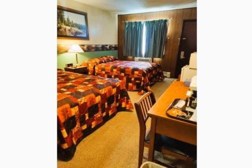 a hotel room with two beds and a desk at Love Hotels Voyageur by OYO at International Falls MN in International Falls
