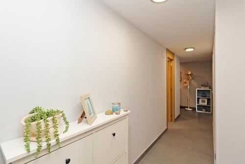 a hallway with white walls and a white cabinet with a plant at GuestReady - Lovely home close to Platja del Puig in El Puig
