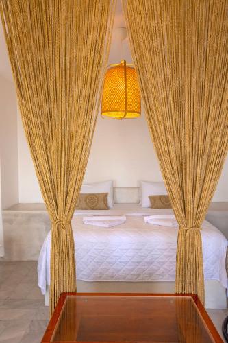a bedroom with a bed with curtains on it at Phaos Santorini Suites in Imerovigli