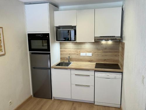 - une petite cuisine avec des armoires et des appareils blancs dans l'établissement Appartement 3 pièces avec piscines, sauna et parking à Samoëns - FR-1-629-106, à Samoëns