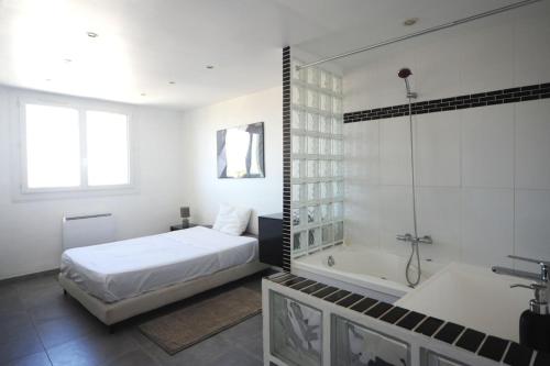 - une chambre blanche avec un lit et une baignoire dans l'établissement Cosy appartement - Longchamp - vue Mer !, à Marseille