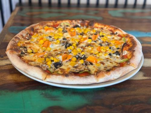a pizza sitting on top of a plate on a table at Hotel Sinner's Shelby in Corabia