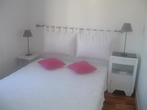 - une chambre avec un lit blanc et 2 oreillers rouges dans l'établissement La Tidette, à Sainte-Marie de Ré