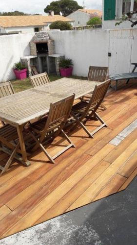 une table et des chaises en bois sur une terrasse en bois dans l'établissement La Tidette, à Sainte-Marie de Ré