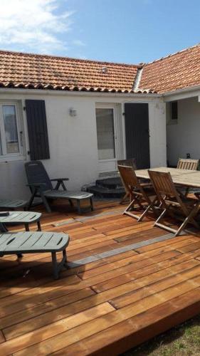 une terrasse en bois avec des chaises, une table et des bancs dans l'établissement La Tidette, à Sainte-Marie de Ré