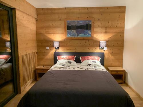 - une chambre dotée d'un lit avec des murs en bois et 2 lampes dans l'établissement Le Samoëns cosy 3 etoiles en centre ville, à Samoëns
