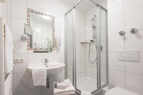 a white bathroom with a shower and a sink at Gästehaus Zehmerhof bei Erding in Walpertskirchen